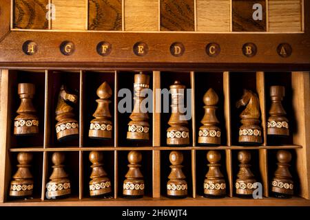 Dunkle Schachfiguren liegen in einer Schachtel. Ein Puzzle-Spiel mit kniffligen Kombinationen, die Planung und Denken erfordert. Stockfoto