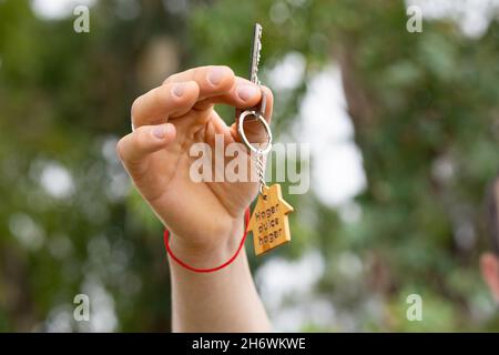 Hand zeigt Schlüssel mit Schlüsselanhänger eines Mini House.New Home Konzept. Stockfoto