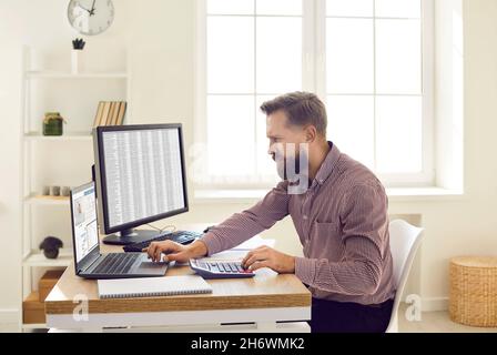 Finanzbuchhalter mit Computern und Taschenrechner während der Arbeit am Schreibtisch im Büro Stockfoto