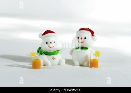 Weihnachten Hintergrund. Fröhliche Schneemänner mit tropischen Drinks, auf weißem Hintergrund mit harten Schatten. Frohe weihnachten und eine Grußkarte zum guten neuen Jahr. I Stockfoto