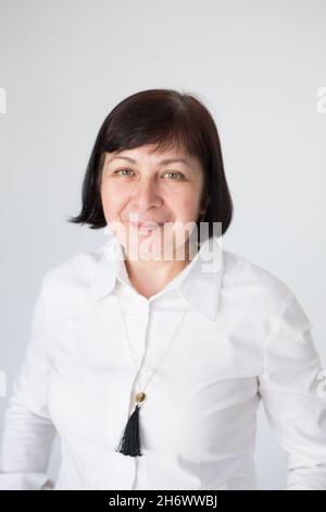 Porträt einer 50-jährigen Frau, mit kurzem Haarschnitt, in einem weißen Hemd. Ein moderner und unabhängiger Erwachsener mittleren Alters, vor schwarzem Hintergrund. Stockfoto