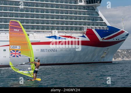 Tom Squires surfing am 21st. Juli 2020 in Portland, Dorset, Großbritannien, am MV Britannia P&O-Kreuzschiff in Weymouth Bay vorbei. Stockfoto