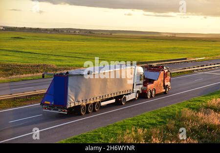 Heavy Recovery Truck schlepper einen Sattelschlepper auf der Autobahn. Rettungswrecker Tow Truck Bus schleppen Auto auf der Straße. Fahrzeug während der Arbeit abschleppen. Сa Stockfoto