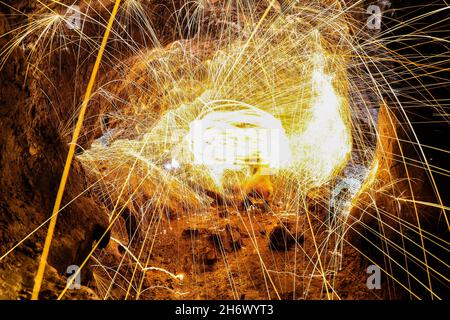 Dies ist eine Langzeitaufnahme von schwingender Stahlwolle in einer Höhle, wenn sie in Brand gesetzt wird. Stockfoto