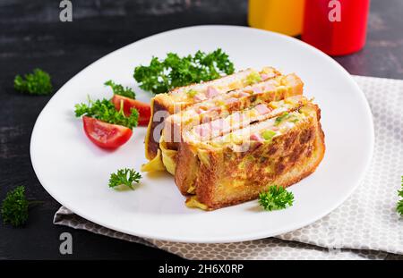 Gebratener Sandwich-Käse, hm, Paprika und Rührei auf weißem Teller. Dunkler Hintergrund. Stockfoto