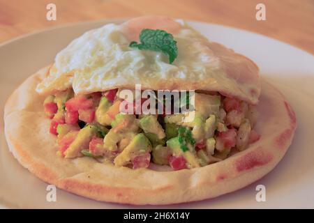 Einfaches und gesundes vegetarisches Frühstück mit Pita-Brot mit frischem Avocado- und Tomatensalat und Spiegelei Stockfoto