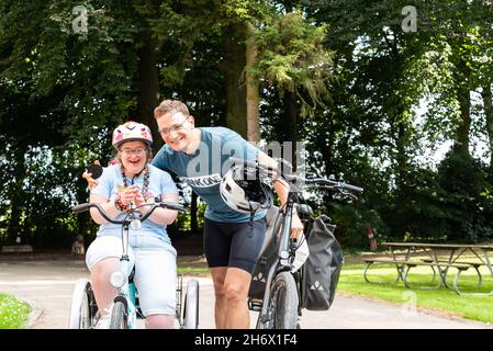 Hapendover, Flämisch-Brabant, Belgien - 09 20 2021: 39-jährige Frau mit Down-Syndrom und ihr Bruder glücklich auf dem Fahrrad