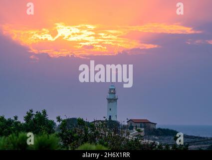 Die Sonne geht hinter dem Leuchtturm von Paphos, Paphos, Zypern, unter. Stockfoto