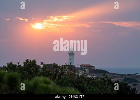 Die Sonne geht hinter dem Leuchtturm von Paphos, Paphos, Zypern, unter. Stockfoto