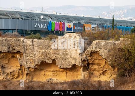 Blick auf die Fassade des Einkaufszentrums Kings Avenue Mall und Werbeschilder, die über der archäologischen Stätte Neo Pafos in Paphos, Zypern, ragen Stockfoto