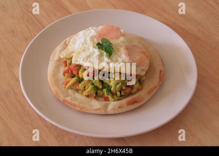 Einfaches und gesundes vegetarisches Frühstück mit Pita-Brot mit frischem Avocado- und Tomatensalat und Spiegelei Stockfoto