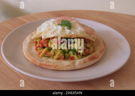 Einfaches und gesundes vegetarisches Frühstück mit Pita-Brot mit frischem Avocado- und Tomatensalat und Spiegelei Stockfoto