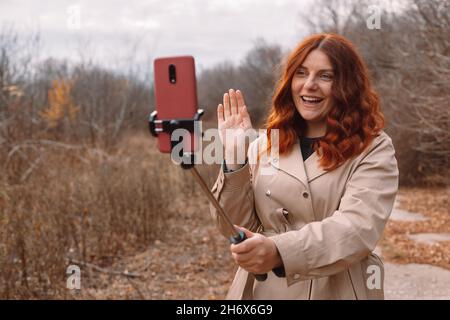 Schöne rothaarige lockiges Haar Mädchen posiert unter Selfie-Foto im Herbst Park Stockfoto