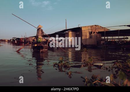 Rückansicht einer Person in einem Boot, die entlang des Wassers paddelt und das tägliche Leben und die Kultur im Mekong-Delta in Vietnam zeigt Stockfoto