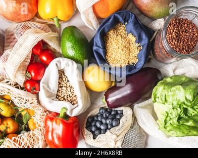 Frisches Gemüse und Obst in Öko-Baumwollbeuteln und Getreide in Gläsern auf dem Tisch in der Küche. Zero Waste Shopping-Konzept. Draufsicht. Flach liegend Stockfoto