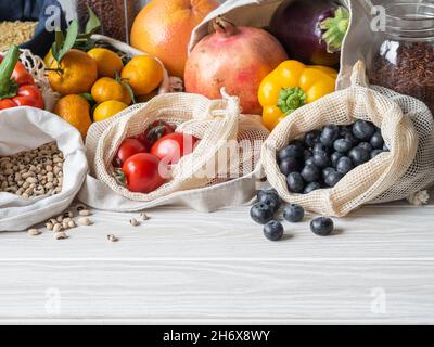 Frisches Gemüse und Obst in Öko-Baumwollbeuteln auf dem Tisch in der Küche. Zero Waste Shopping-Konzept. Vorderansicht. Speicherplatz kopieren. Stockfoto