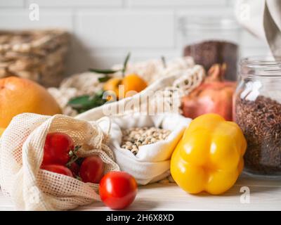 Frisches Gemüse und Obst in Öko-Baumwollbeuteln auf dem Tisch in der Küche. Zero Waste Shopping-Konzept. Vorderansicht. Speicherplatz kopieren. Stockfoto