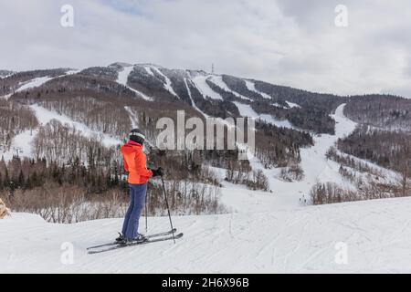 Skifahrerin. Alpine Ski - Skifahrer mit Blick auf die Berge gegen schneebedeckte Bäume und Ski im Winter. Mont Tremblant, Quebec, Kanada. Stockfoto