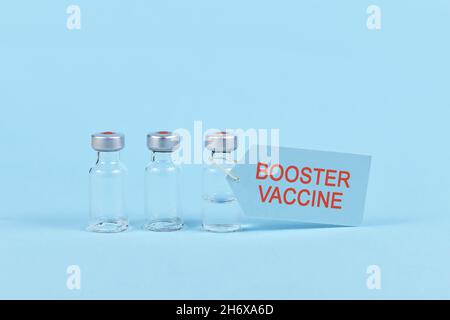 Corina Virus Booster Impfkonzept mit Fläschchen und Spritze auf blauem Hintergrund Stockfoto