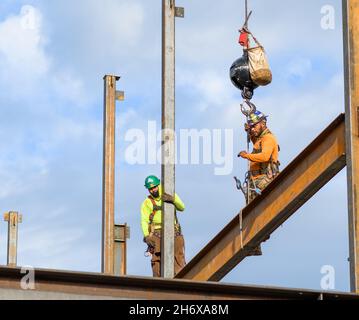 NEW ORLEANS, LA, USA - 17. NOVEMBER 2021: Zwei Bauarbeiter entfernen einen Stahlträger von einer Krankugel und Haken Stockfoto