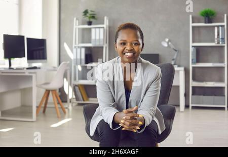 Porträt einer lächelnden afroamerikanischen Geschäftsfrau, die auf einem Stuhl sitzt Stockfoto