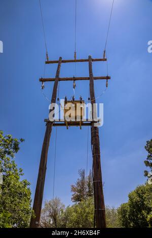 Vertikale Weitwinkelaufnahme eines elektrischen Transformators hoch oben auf Holzmasten Stockfoto