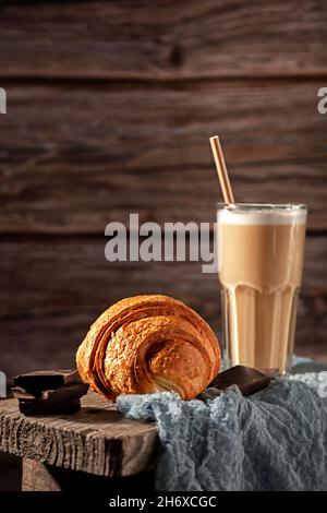 Frisch gebackenes duftendes Croissant mit Kakao in einem Glas auf Holzboden Stockfoto