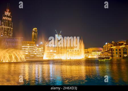 DUBAI, VAE - 3. MÄRZ 2020: Die nächtliche Aufführung des Dubai Fountain mit der Dubai Mall und dem Al Bahar Souk hinter dem Burj Lake, am 3. März in Dubai Stockfoto