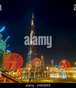 DUBAI, VAE - 3. MÄRZ 2020: Die großartige Aussicht auf den Burj Khalifa-Turm und leuchtende, farbenfrohe Dandelions-Skulpturen im Burj Park, am 3. März in Dubai Stockfoto