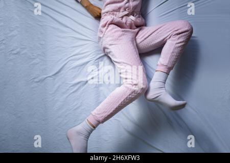 Afroamerikanische Frau mit RLS - Restless Legs Syndrom. Schlafen Im Bett Stockfoto