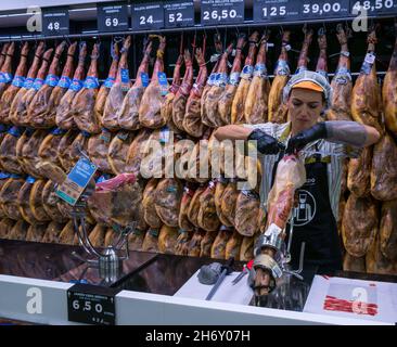 Frau carving Schinken mit geräuchertem Schinken Beine im Supermarkt, Nerja, Andalusien, Spanien Stockfoto