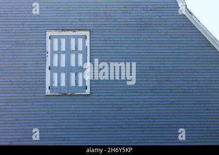 Nahaufnahme eines altmodischen versperrten Fensters mit klappbaren Fensterläden in einem alten Haus. Stockfoto