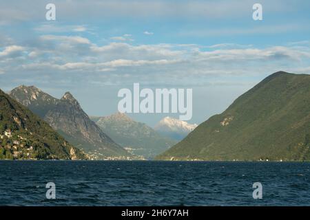 Lugano, Schweiz - 6th 2021. Oktober: Lago di Lugano mit umliegenden Hügeln und Bergen im Nachmittagssonne. Stockfoto