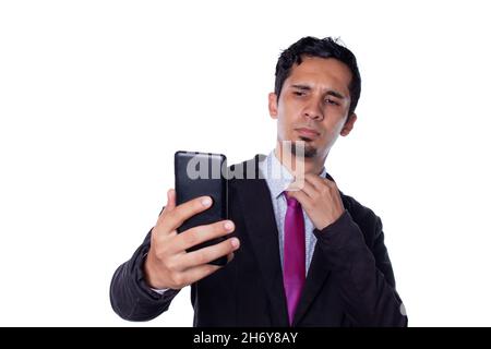 Attraktiver Geschäftsmann posiert und fotografiert mit seinem Handy. Junger junger, erwachsener mann aus latein, isoliert auf weißem Hintergrund. Stockfoto
