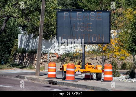 Solar-Handy-Schild mit orangefarbenen Kegeln sitzen auf Bürgersteig neben der Straße sagen Bitte verwenden Sie Vorsicht - selektive Fokus Stockfoto