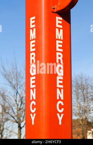 Edmonds, WA, USA - 17. November 2021; ein orangefarbener Metallpfosten mit dem Wort Emergency auf jeder Seite in weißen Buchstaben vor einem blauen Himmel Stockfoto