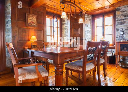 Antiker Esstisch aus Holz mit beigefarbenem Polsterholz und schwarzen, geschmiedeten Stahlstühlen mit gestickten goldenen Motiven im Speisesaal des alten Hauses aus dem Jahr 1750 Stockfoto