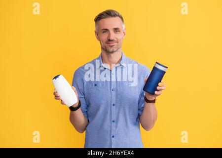 Guy wählen Shampoo-Flasche oder Haarspülung. Tägliche Gewohnheiten und persönliche Pflege. Stockfoto