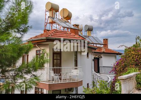 Konzept spart Strom. Dach von Häusern mit Sonnenkollektoren und Wasserfässern. Solarenergie. Stockfoto