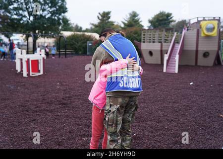 28. Oktober 2021 - Joint Base McGuire-Dix-Lakehurst, New Jersey, USA - Ein Dienstmitglied, das der Task Force Liberty zugewiesen ist, umarmt ein afghanisches Kind in einem Park im Liberty Village, während es die Operation Allies unterstützt Willkommen auf der Joint Base McGuire-Dix-Lakehurst, New Jersey, 28. Oktober 2021. Das Verteidigungsministerium stellt über das Northern Command der USA und zur Unterstützung des Heimatschutzministeriums so schnell wie möglich Transport, vorübergehende Unterbringung, medizinische Vorsorgeuntersuchungen und allgemeine Unterstützung für mindestens 50,000 afghanische Evakuierte in geeigneten Einrichtungen in permanenten oder temporären Strukturen bereit. Thi Stockfoto