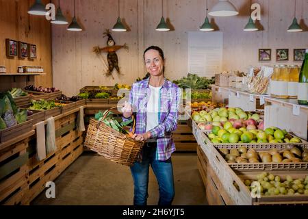 Portrait von schönen Brünette Mädchen Wahl Obst und Gemüse auf dem Bauernmarkt. Nachhaltiger Lebensstil Stockfoto