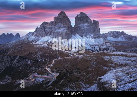 Dramatische Abendlandschaft mit drei Gipfeln der Lavaredo-Berge, glühender Straße und rosa Sonnenuntergangshimmel. auronzo refugio im Nationalpark Tre Cime Di Lavaredo, Dolomiten, Trentino-Südtirol, Italien Stockfoto