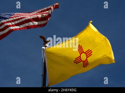 Die Staatsflagge von New Mexico mit ihrem indianischen Sonnensymbol fliegt neben einer Flagge der Vereinigten Staaten in Santa Fe, New Mexico. Stockfoto