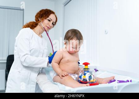 Kinderarzt Arzt Konzept. Medizinische Versorgung von Kindern. Ein Jahr altes Mädchen, das von einer Kinderärztin im Klinikbüro untersucht wurde. Kind besucht Arzt für Stockfoto