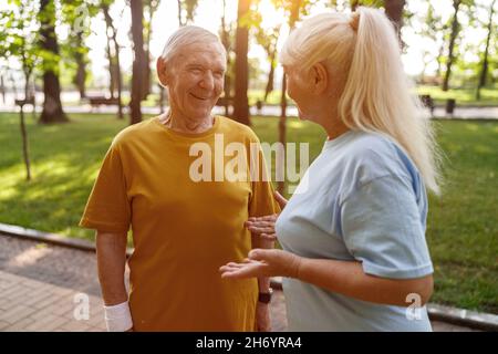 Sportliche ältere Männer und Frauen kommunizieren beim Training im Park Stockfoto