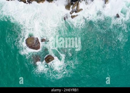 Luftaufnahme der Wellen am Meer Weiße schäumende Wellen auf den Felsen am Meer Draufsicht fantastische Rocky Coast erstaunliche Natur Hintergrund Stockfoto