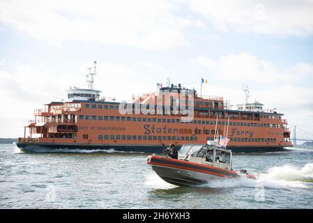 Ein Team der Küstenwache für die Sicherheit und den Schutz des Seeverkehrs, eine Crew der New Yorker Bootsmannschaft, begleitet eine Fähre im Hafen von New York, 21. September 2021. Das MSST New York befindet sich in Kooperation mit der Coast Guard Station New York in Staten Island, New York. (USA Foto der Küstenwache von Petty Officer 2nd Klasse Cory J. Mendenhall) Stockfoto