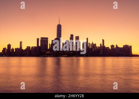 New York, NY - USA - Nov 14, 2021: Waagerechte, frühmorgendliche Ansicht der Skyline von New York City bei Sonnenaufgang, mit goldenen Reflexen des World Trade C Stockfoto