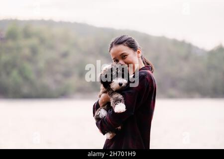 An einem warmen Sommertag umarmt sich der Schäferhund und mit der Frau auf einem Dock am See Stockfoto
