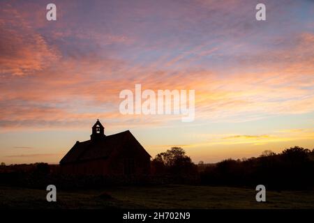 Morgengrauen Herbsthimmel vor Sonnenaufgang über St. Oswald's Kirche. Widford, Cotswolds, Oxfordshire, England Stockfoto